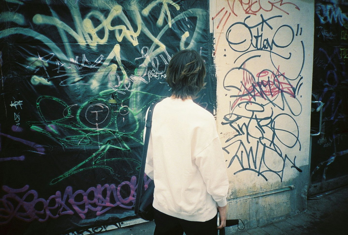 Eine Person steht vor einer bunten Graffiti-Wand.